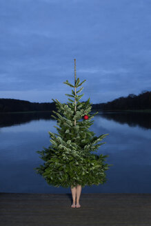 Woman standing behind Christmas tree on jetty - PSTF00056