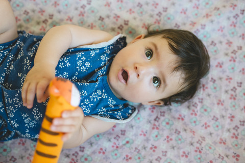 Baby girl playing with a tiger-shaped rattle stock photo