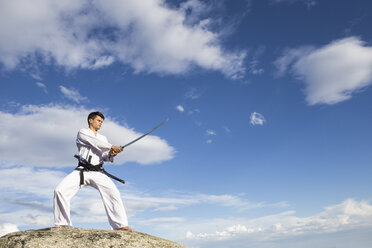 Man holding a katana sword on a rock - ABZF02127