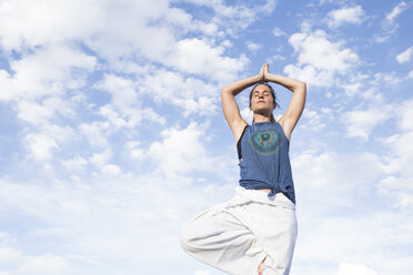 Frau macht eine Yoga-Übung unter Himmel mit Wolken - ABZF02128