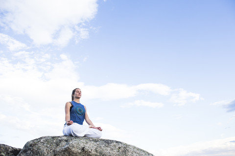 Woman doing yoga sitting on a rock stock photo