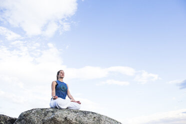 Frau beim Yoga auf einem Felsen sitzend - ABZF02129