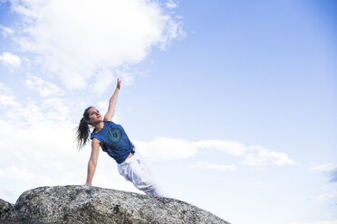 Frau bei einer Yoga-Übung auf einem Felsen - ABZF02130