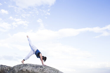 Frau bei einer Yoga-Übung auf einem Felsen - ABZF02132