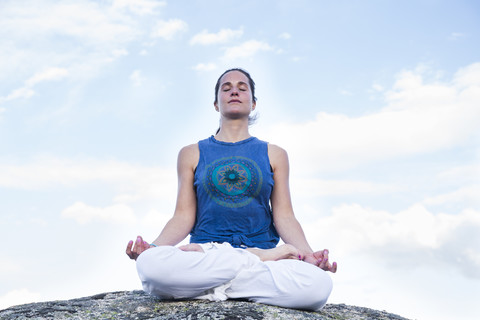 Woman doing yoga sitting on a rock stock photo