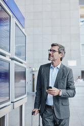 Geschäftsmann mit Handy am Fahrplan auf dem Flughafen - RORF00884