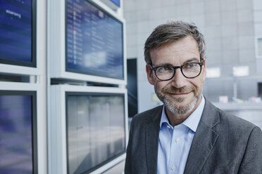 Lächelnder Geschäftsmann am Fahrplan auf dem Flughafen - RORF00886