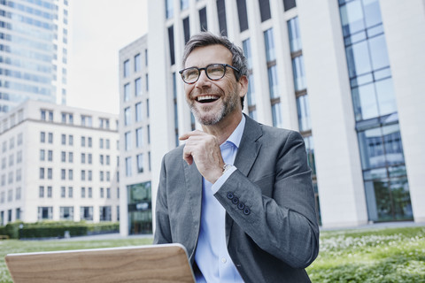 Glücklicher reifer Geschäftsmann im Freien mit Laptop im Freien, lizenzfreies Stockfoto