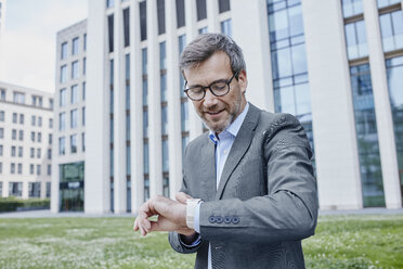 Reifer Geschäftsmann im Freien, der seine Smartwatch überprüft - RORF00891
