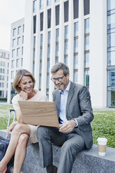 Glückliche Geschäftsfrau und Geschäftsmann teilen sich einen Laptop im Freien - RORF00898