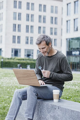 Älterer Mann im Freien mit Laptop und Kaffee zum Mitnehmen - RORF00932