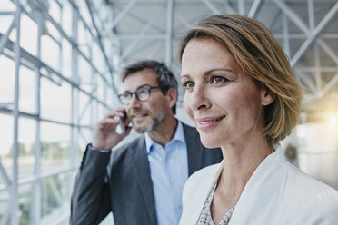 Smiling businesswoman and businessman on cell phone at the airport - RORF00943