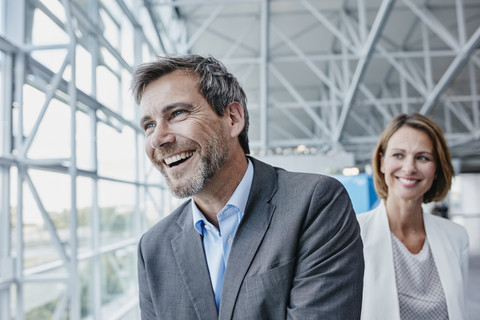 Glücklicher Geschäftsmann und glückliche Geschäftsfrau auf dem Flughafen, lizenzfreies Stockfoto