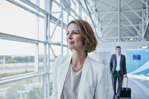 Selbstbewusste Geschäftsfrau auf dem Flughafen, die aus dem Fenster schaut, lizenzfreies Stockfoto