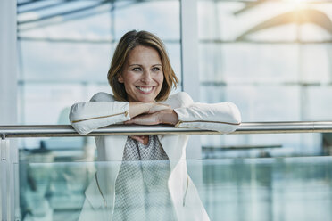 Happy businesswoman leaning on railing at the airport - RORF00957