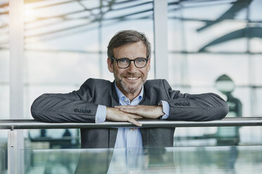 Portrait of smiling businessman leaning on railing at the airport - RORF00959