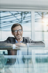 Happy businessman leaning on railing at the airport - RORF00961