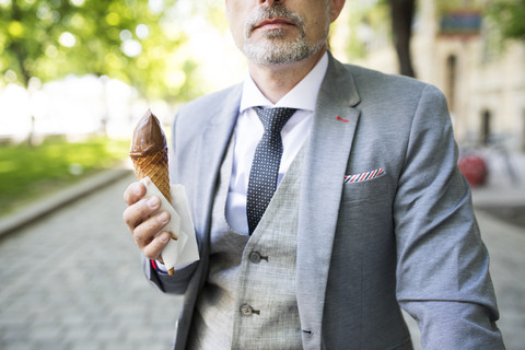 Reifer Geschäftsmann in der Stadt isst Eiscreme, lizenzfreies Stockfoto