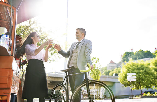 Geschäftsmann mit Fahrrad kauft Kaffee zum Mitnehmen auf der Straße - HAPF01708