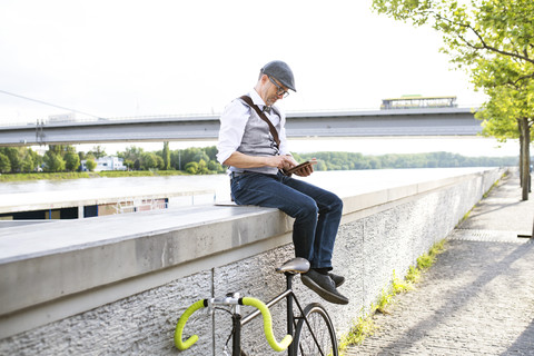 Geschäftsmann mit Fahrrad und Tablet am Flussufer, lizenzfreies Stockfoto