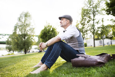 Mature businessman in the city park sitting on grass - HAPF01727