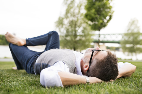 Mature businessman in the city park lying on grass stock photo