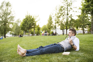Mature businessman in the city park lying on grass - HAPF01742