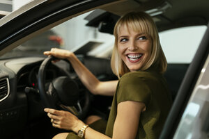 Blond woman choosing new car in car dealership - ZEDF00673