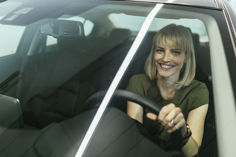 Blonde Frau wählt neues Auto im Autohaus aus, lizenzfreies Stockfoto