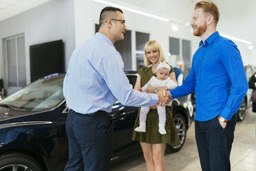 Family meeting seller of family vehicle in car dealership - ZEDF00678