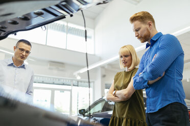 Salesman advising customers in car dealership - ZEDF00693