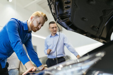 Salesman advising customer in car dealership - ZEDF00695