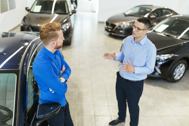 Salesman advising customer in car dealership - ZEDF00700