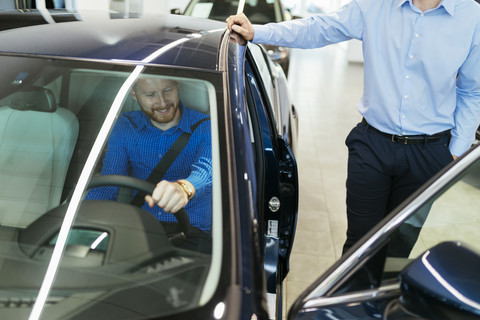 Salesman advising customer in car dealership stock photo