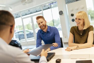 Salesperson advising couple in car dealership - ZEDF00704