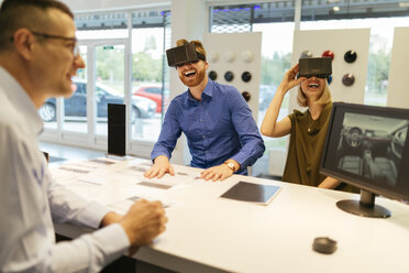 Couple using VR glasses in car dealership - ZEDF00707