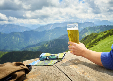 Deutschland, Chiemgau, Hand eines Wanderers auf dem Hochfelln, der ein Bierglas hält, Teilansicht - DIKF00253