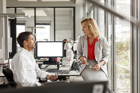 Businesswoman and businessman discussing at desk in office stock photo