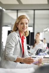Porträt einer lächelnden Geschäftsfrau am Schreibtisch im Büro mit einem futuristischen Tablet - PESF00716