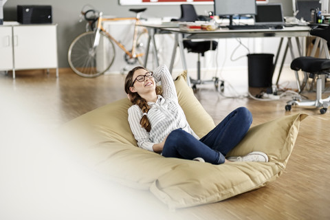 Young woman relaxing in bean bag in office stock photo