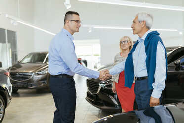 Älteres Ehepaar im Gespräch mit einem Verkäufer in einem Autohaus - ZEDF00723