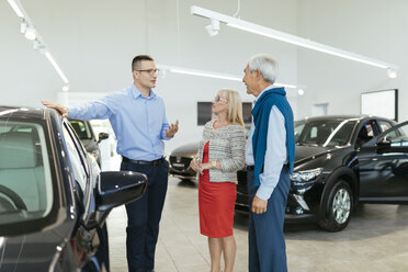 Älteres Ehepaar im Gespräch mit einem Verkäufer in einem Autohaus - ZEDF00724