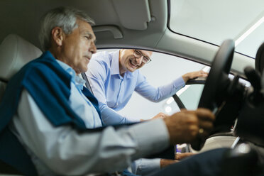 Salesman advising customer in car dealership - ZEDF00726