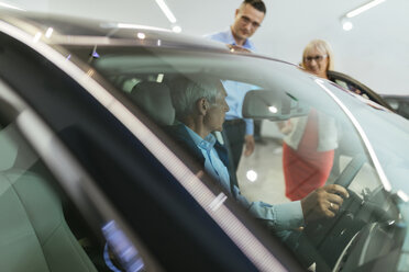 Älteres Ehepaar im Gespräch mit einem Verkäufer in einem Autohaus - ZEDF00727