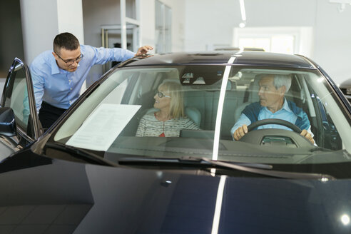 Salesman advising customers in car dealership - ZEDF00730