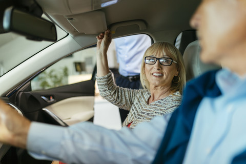Senior couple trying out car in car dealership stock photo