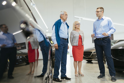 Senior couple couple talking with salesperson in car dealership stock photo