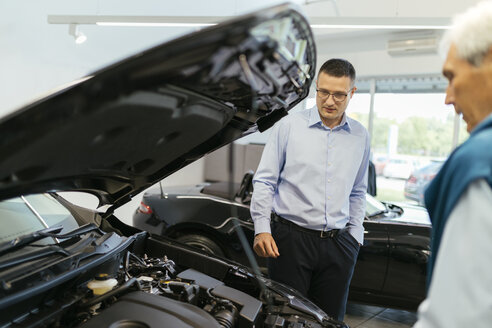 Verkäufer, der einen Kunden im Autohaus berät - ZEDF00736