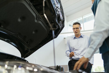 Salesman advising customer in car dealership - ZEDF00737