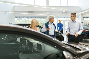 Salesman advising customers in car dealership - ZEDF00738